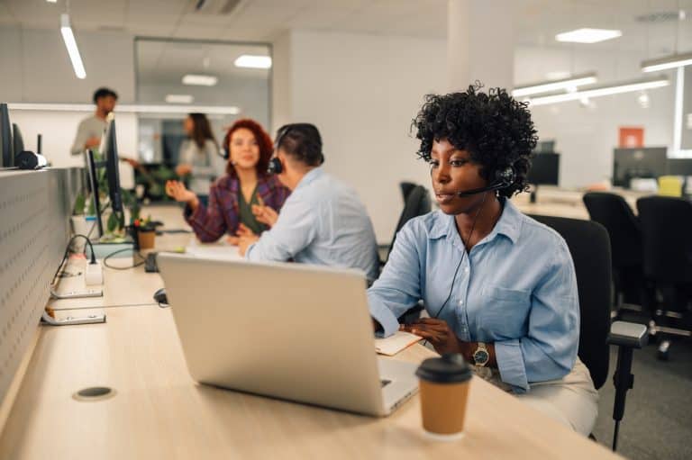 Femme travaillant dans un centre d'appels avec des collègues.