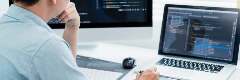Développeur travaillant sur deux écrans avec code.