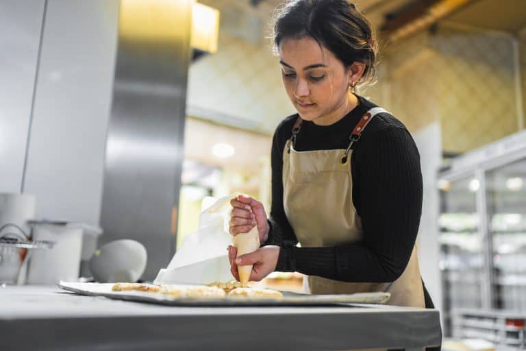 Femme préparant des pâtisseries en cuisine professionnelle.