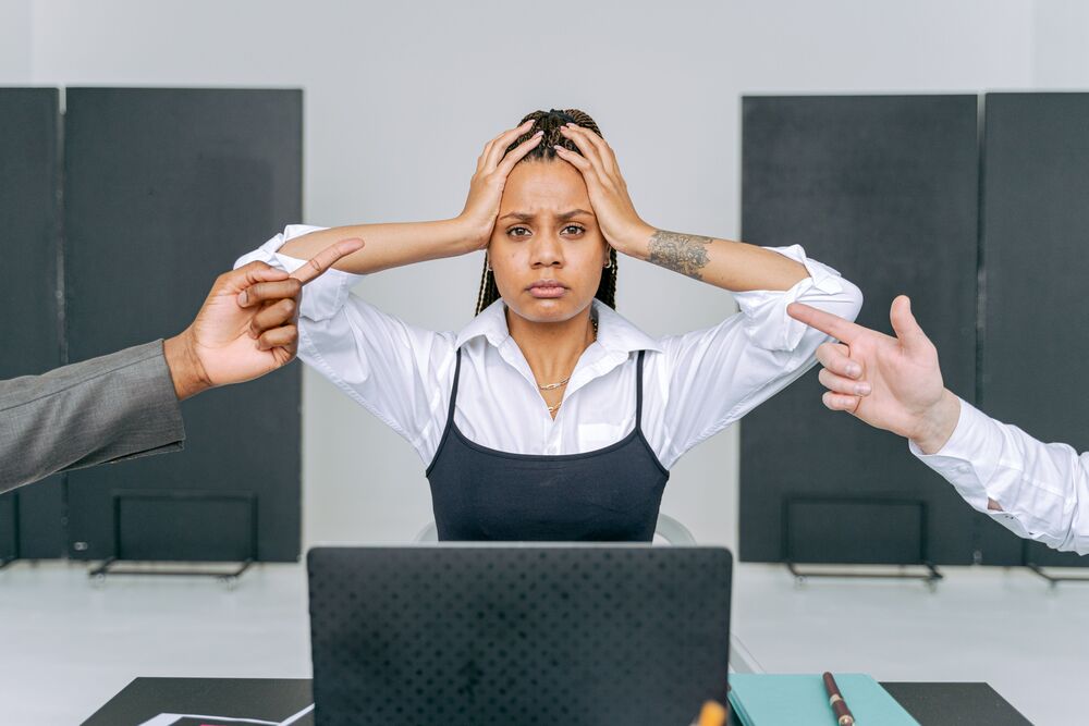 Femme stressée au travail face à des doigts pointés.